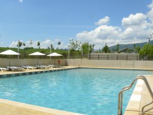 una gran piscina con sillas y sombrillas en APARTMENTSUITESPAIN FORMIGAL ORDESa, en Sabiñánigo