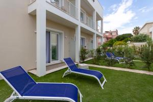 a group of blue chairs sitting on a lawn in front of a building at Hotel Nautilus in Cagliari