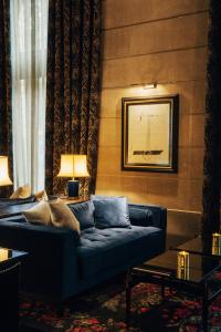 a living room with a blue couch in a room at Hotel Bagués, a Small Luxury Hotel of the World in Barcelona