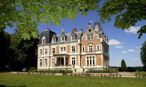 duży ceglany budynek z niebieskim niebem w tle w obiekcie Château De L'aubrière - Les Collectionneurs w mieście La Membrolle-sur-Choisille