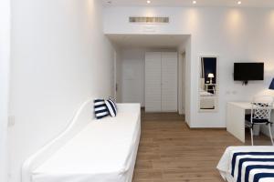 a white bedroom with a white bed and a desk at Hotel Nautilus in Cagliari