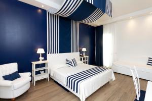 a bedroom with blue walls and a bed and a chair at Hotel Nautilus in Cagliari