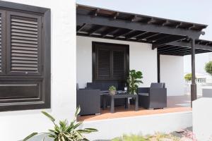 een patio met een zwarte pergola en stoelen bij Apartamento playa coqueto junto al mar in Playa Honda