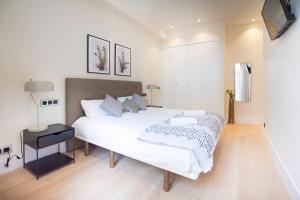 een slaapkamer met een groot wit bed en een televisie bij Minty Stay - Paz in Madrid