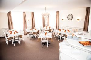 a restaurant with white tables and chairs and windows at Hotel Adler in Eichstätt