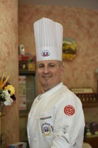 un homme portant un chapeau de chef dans une cuisine dans l'établissement Il FEUDO, à San Gimignano