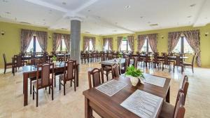 a restaurant with wooden tables and chairs and windows at Warmiński Zakątek in Olsztyn