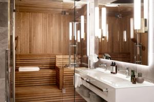 ein Bad mit einer Dusche, einem Waschbecken und einem Spiegel in der Unterkunft Hotel St. George Helsinki in Helsinki