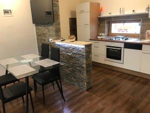 a kitchen with a table and a stone wall at Candy Apartman in Keszthely
