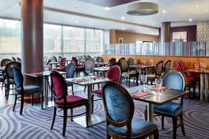 ein Restaurant mit Tischen, Stühlen und Fenstern in der Unterkunft Leonardo Hotel Newcastle Quayside - Formerly Jurys Inn in Newcastle upon Tyne