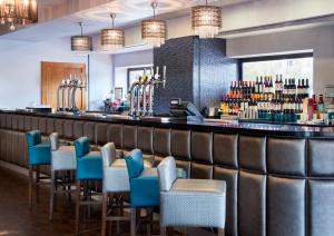 a bar at a restaurant with blue chairs at Leonardo Hotel Newcastle Quayside in Newcastle upon Tyne