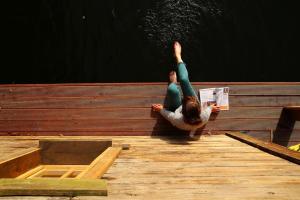 a person is laying on a wooden dock with their hands in the air at Pływający Domek in Przywidz