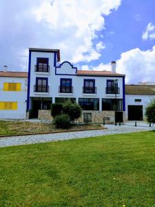 a white building with black windows and a green field at Sol Mar in Odeceixe
