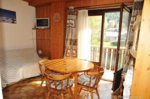 a wooden table and chairs in a room with a window at 2 pièces Les Iris 20 Station Thollon les Mémises in Thollon