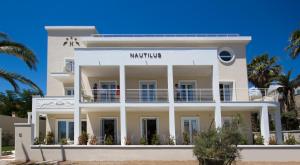 a white building on the beach with palm trees at Hotel Nautilus in Cagliari