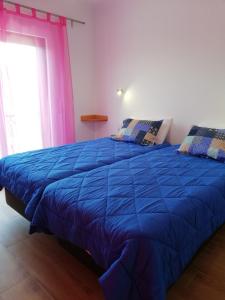 a blue bed in a room with a window at Sol Mar in Odeceixe
