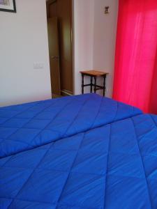 a blue bed in a room with a red curtain at Sol Mar in Odeceixe