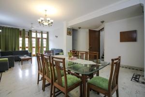 comedor y sala de estar con mesa de cristal y sillas en Under My Roof Green Park, en Nueva Delhi