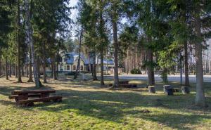 a park with picnic tables and trees and a house at Motel Brencis in Iecava