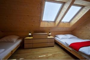 two beds in a wooden room with two windows at Nadmorski Skarb Domki Apartamentowe in Ostrowo