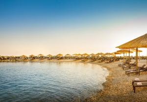 einen Strand mit Tischen, Stühlen und Sonnenschirmen in der Unterkunft Laguna Maradiso Hotel by Aminess in Novigrad Istria