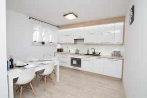 a kitchen with white cabinets and a table and chairs at Apartament Laura in Hel