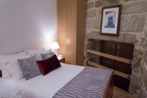 a bedroom with a bed with a stone wall at Casa Da Trigueira in Santa Eugénia