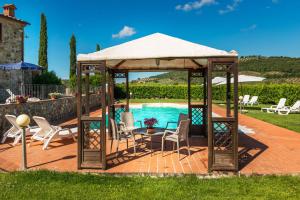 a gazebo with chairs and a table next to a pool at Agriturismo Pian del Vescovo in Massa Marittima