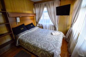 1 dormitorio con 1 cama, TV y ventana en Hostal Parediso, en Punta Arenas