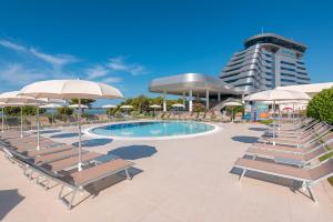 a pool with chairs and umbrellas and a building at Hotel Olympia Sky in Vodice