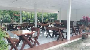 a group of wooden tables and chairs on a patio at Saeng Tai Amphawa in Samut Songkhram