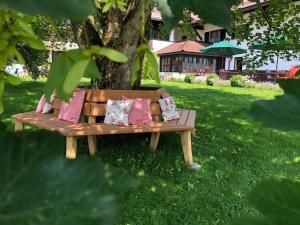 a wooden bench sitting in the grass under a tree at Hotel Bachmair Alpina in Rottach-Egern
