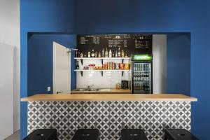 a bar with a blue wall and a counter with drinks at Chesscom Guesthouse in Budapest