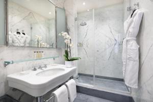 a white bathroom with a sink and a shower at Portrait Roma - Lungarno Collection in Rome