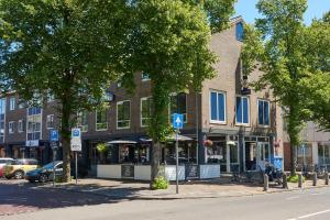 un bâtiment situé dans une rue avec des arbres devant elle dans l'établissement Hotel Restaurant de Jonge Heertjes, à Aalsmeer