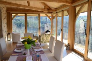 a dining room with a table and chairs and windows at Le Couvent in Saint-Just-sur-Viaur