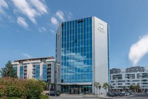 a tall glass building in front of two buildings at Eurostars Gran Hotel Santiago in Santiago de Compostela