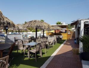 une rangée de tables et de chaises avec parasols en paille dans l'établissement Mobile Home Service Hotelier, à Fréjus