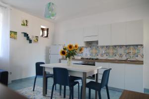 una cocina con una mesa con sillas y un jarrón de flores. en Appartamento Malvasia en Canneto