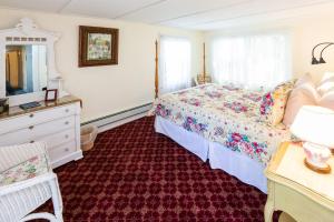 sypialnia z łóżkiem, komodą i lustrem w obiekcie The Elmhurst Inn w mieście Bar Harbor