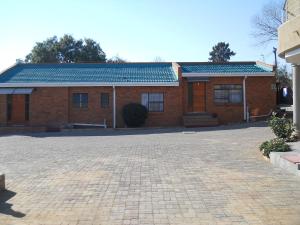 a brick building with a brick driveway in front of it at Noble Hearts Bed & Breakfast in Maseru