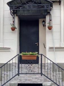 une porte noire avec un pot de fleurs sur une terrasse couverte dans l'établissement Apart-Hotel Shell, à Tbilissi