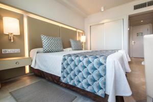 a bedroom with a large bed with blue pillows at Spring Hotel Vulcano in Playa de las Americas