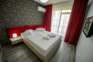 a bedroom with a large bed with red walls and a window at TABU Residence in Mamaia Nord