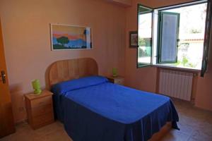 a bedroom with a blue bed and a window at La casa tra i limoni in SantʼAgata di Militello