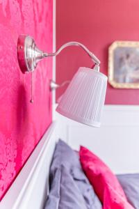 a lamp attached to a pink wall with a bed at Bahnhof Frauenstein Wartehalle in Frauenstein +19 photos