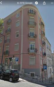 een roze gebouw met een auto ervoor geparkeerd bij Luciano Resident in Lissabon