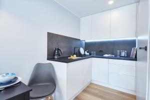 uma cozinha com armários brancos e um balcão preto em Apartamenty Sopot19 em Sopot