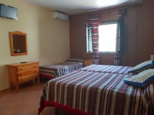 a bedroom with two beds and a dresser and a window at Hostal Pampaneira in Pampaneira