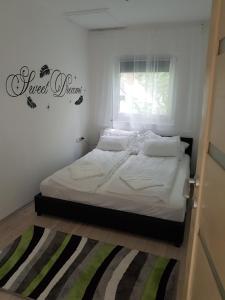 マコーにあるForest Apartmanのベッドルーム1室(白いベッド1台、壁に看板付)